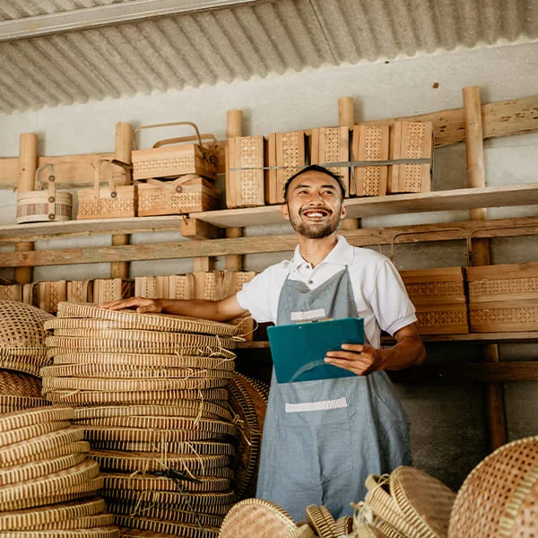 Un homme se tenant devant une pile de paniers, illustrant une scène de marché ou de stockage traditionnel.