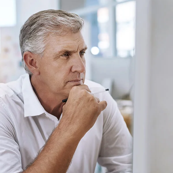 Un homme observe attentivement l'écran de son ordinateur, concentré sur son travail ou ses recherches.