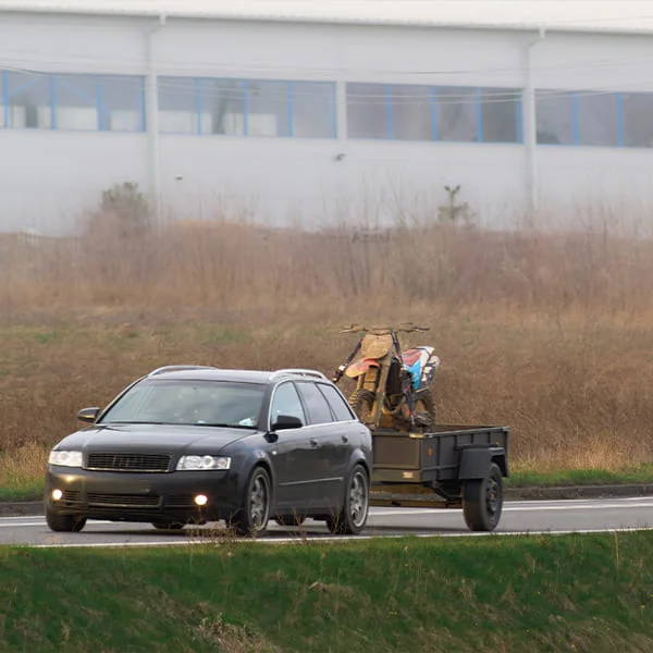 Une voiture circulant sur la route, remorque à cheval accrochée à l'arrière, sous un ciel dégagé.