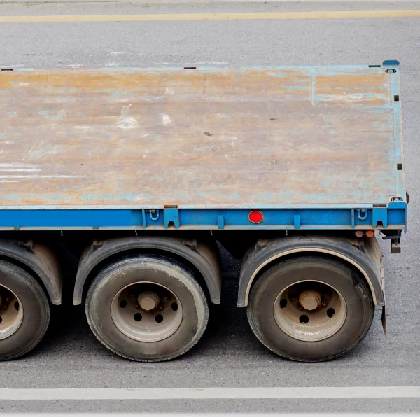 Un camion avec une remorque plateforme, prêt à transporter des marchandises sur une route dégagée.