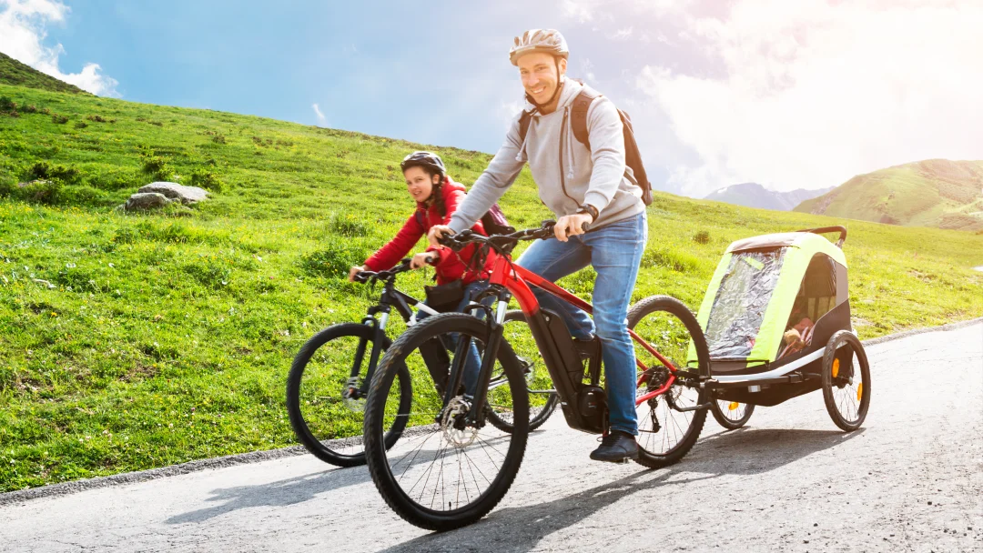 Un homme et une femme font du vélo avec un enfant dans une remorque VTT.