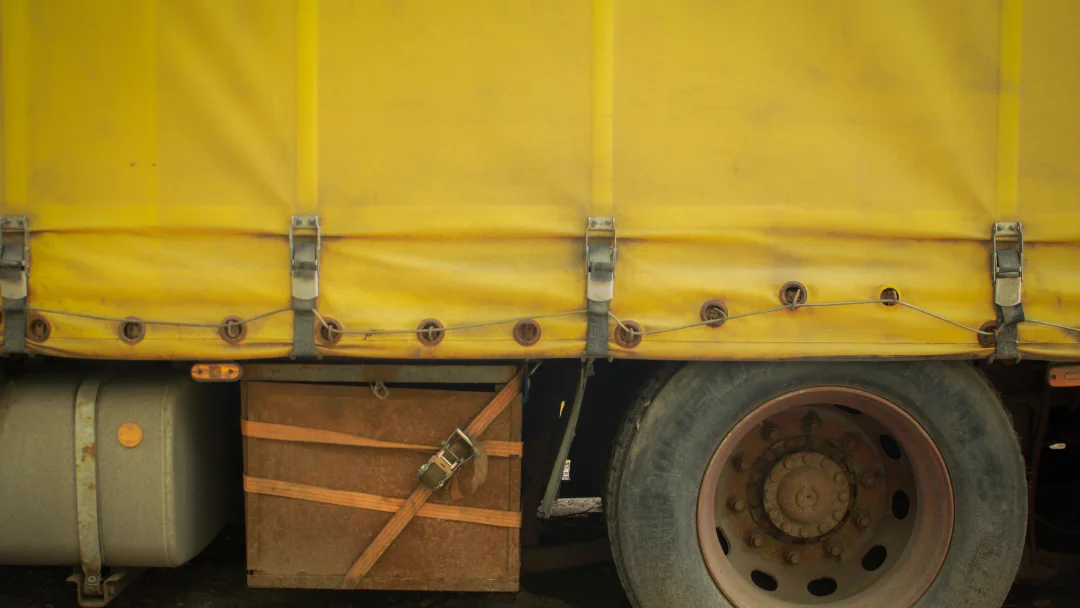 Gros plan sur un camion recouvert d'une toile de remplacement jaune, mettant en avant les détails de la couverture