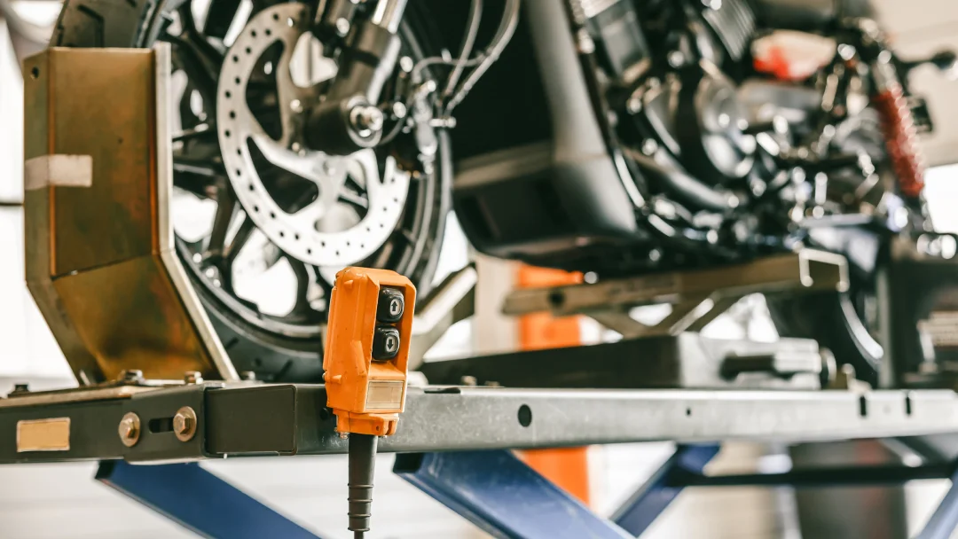 Un mécanicien effectue des réparations sur une moto à l'aide d'un élévateur moto dans un atelier.